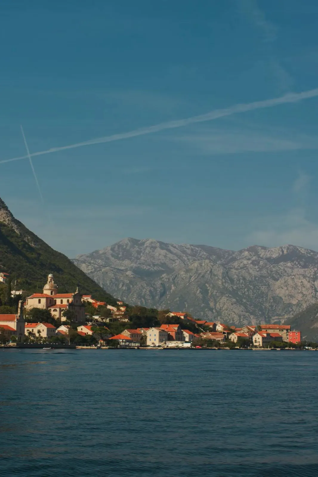 A small town on a bay, mountains behind.