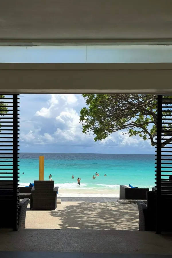 A turquoise beach seen from a shaded pavilion.