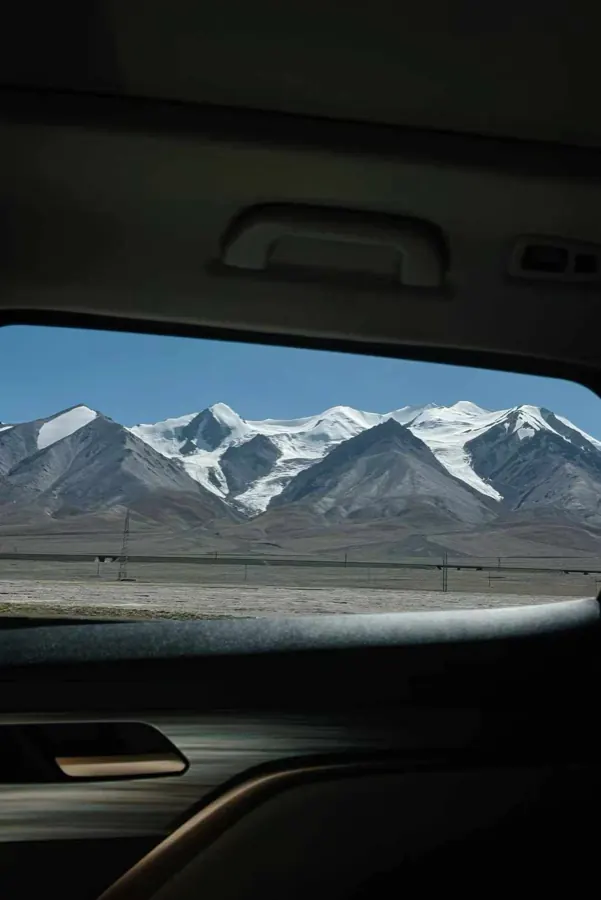 Snow mountains framed by a car window.