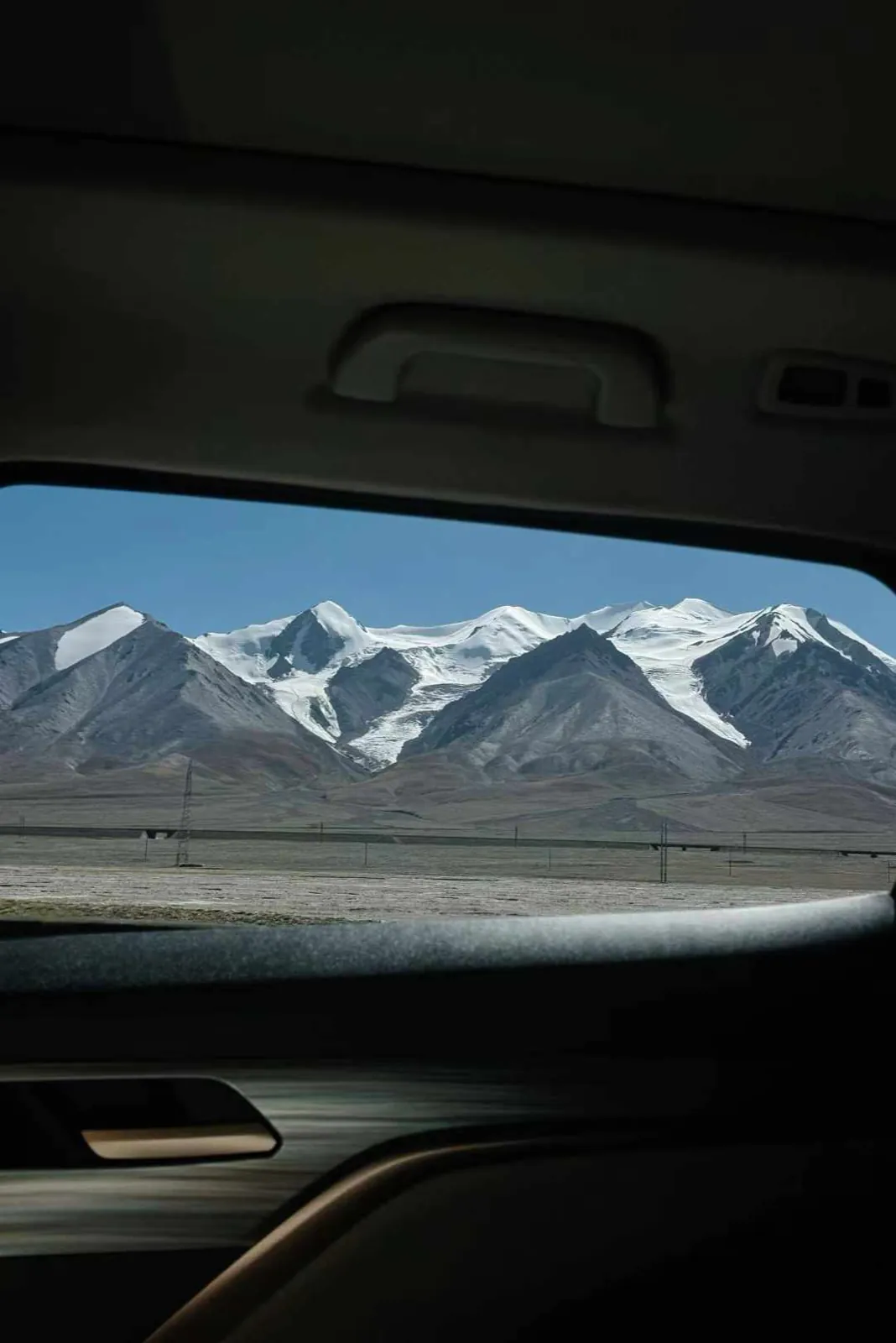 Snow mountains framed by a car window.