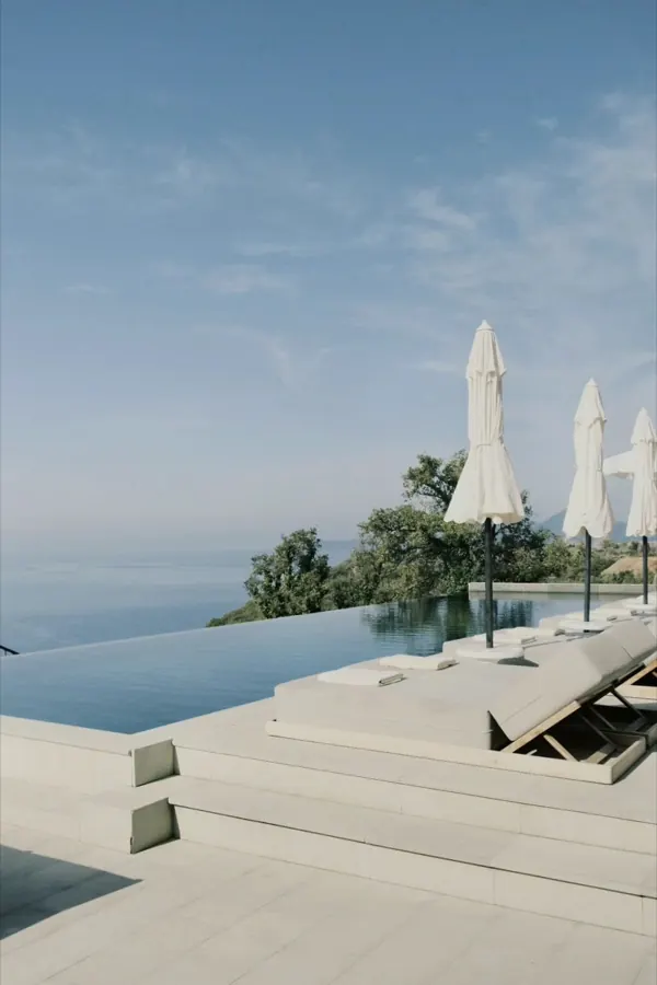An infinity pool above the sea, its white parasols folded.