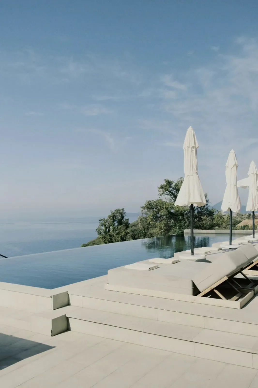 An infinity pool above the sea, its white parasols folded.