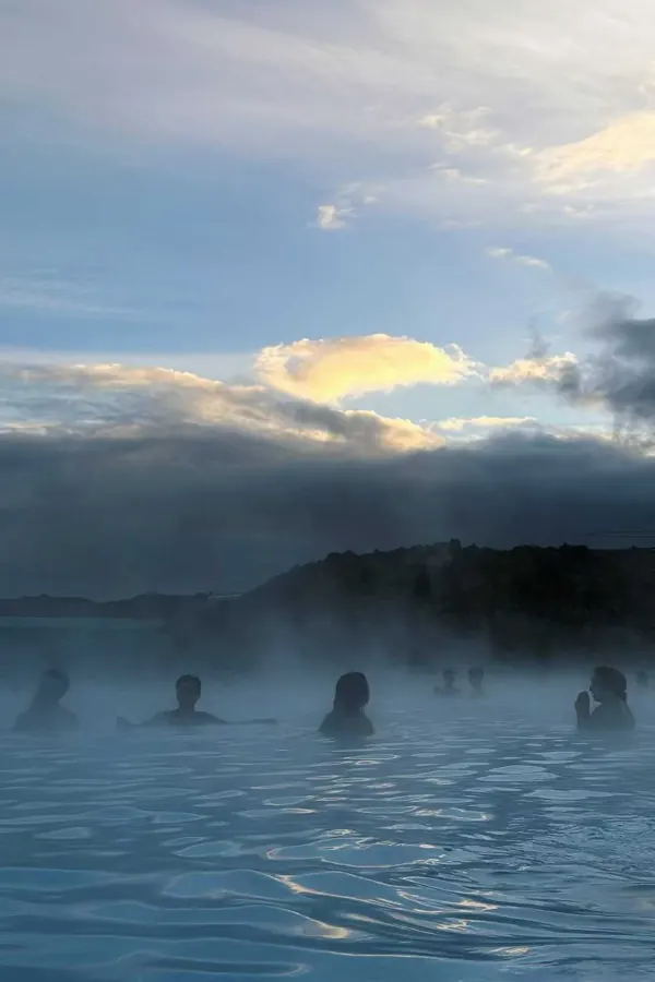 Bathers in a steaming geothermal lagoon under a low sky.