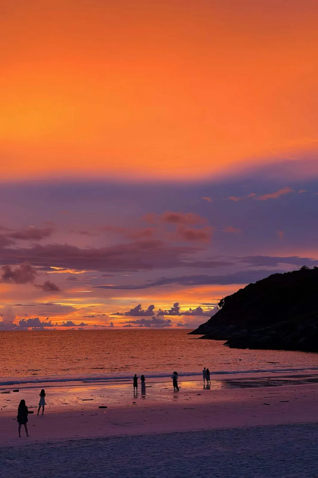 An orange sky over the shore, a dark headland to one side.