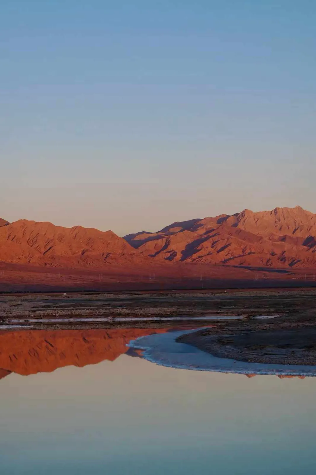 Red mountains mirrored in still water at dusk.