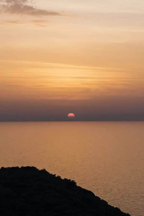 The sun dropping into a hazy sea.