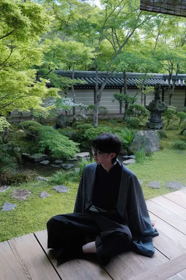 Sitting on a wooden veranda in Japan, a garden behind.