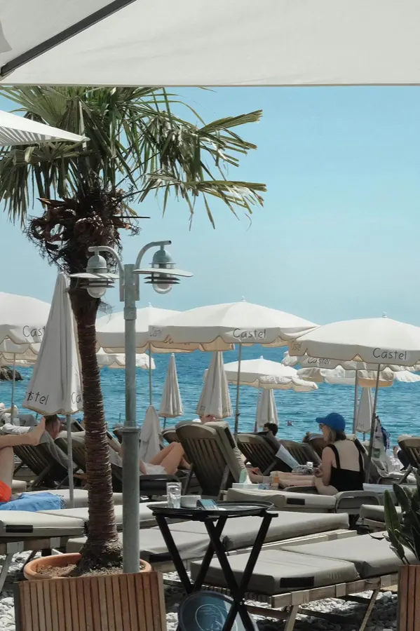 A beach club of palms and white umbrellas.