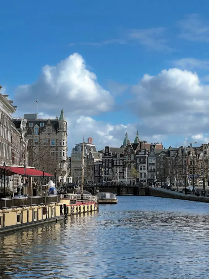 A canal lined with old houses under big clouds.