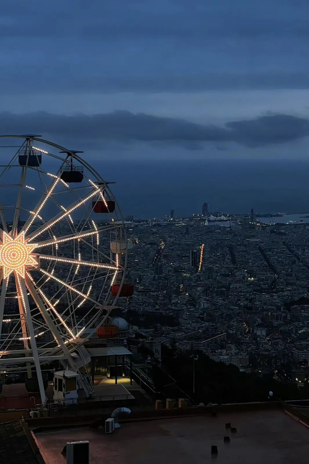 A Ferris wheel above a city at dusk.