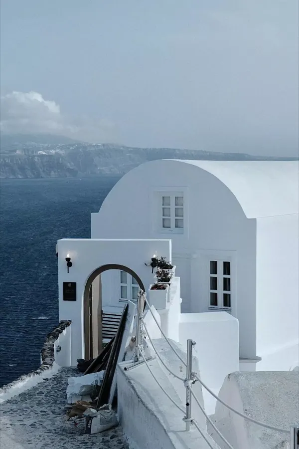 A whitewashed house on a cliff above the sea.