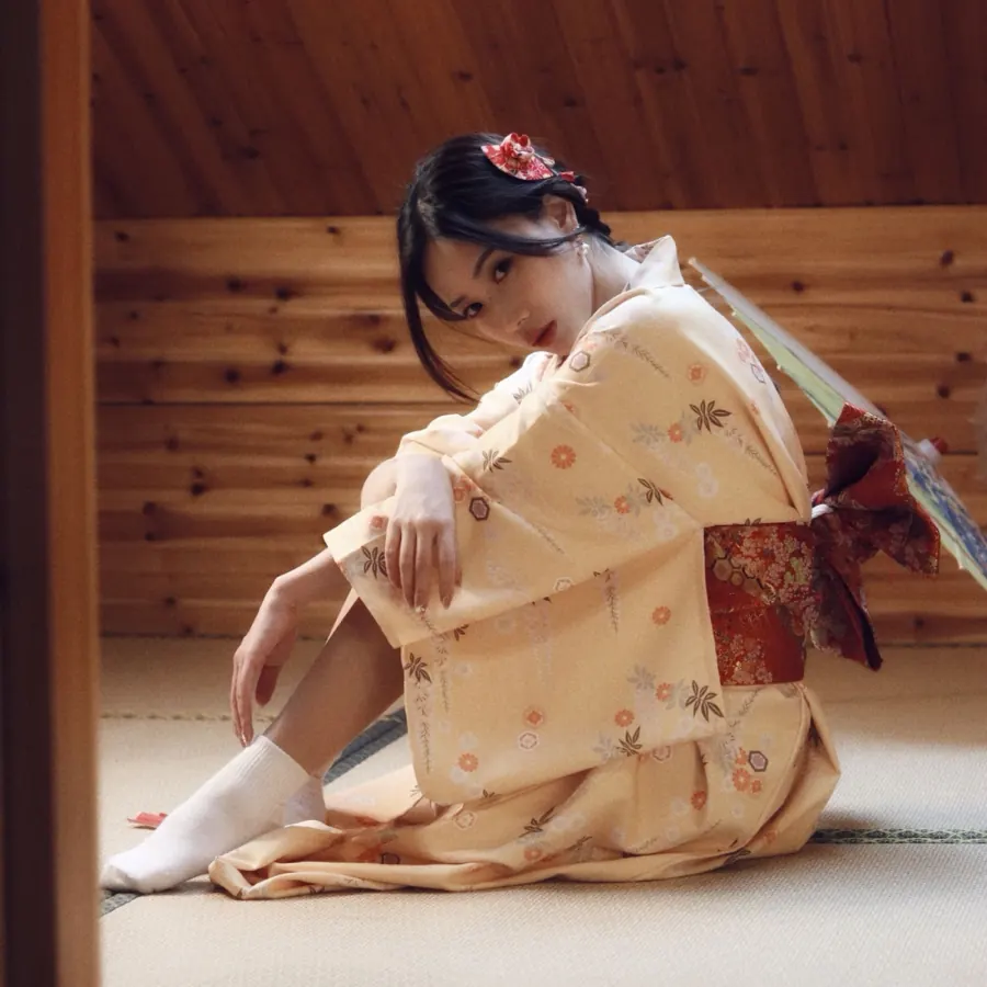 A kimono on a tatami floor, knees drawn up, a paper umbrella behind.