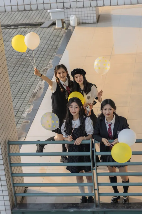 Four friends with yellow balloons, seen from above on a balcony.