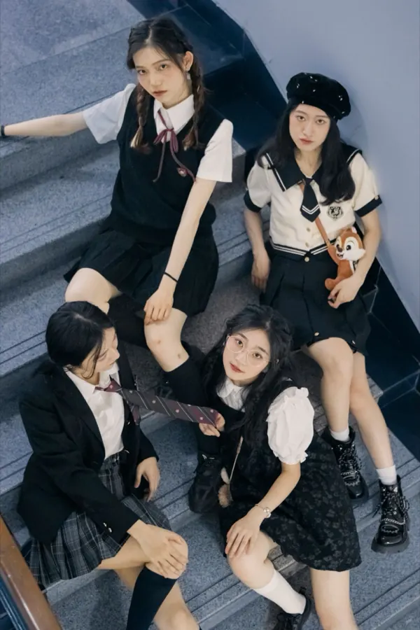 Four friends in school uniforms, sitting on a stairwell.