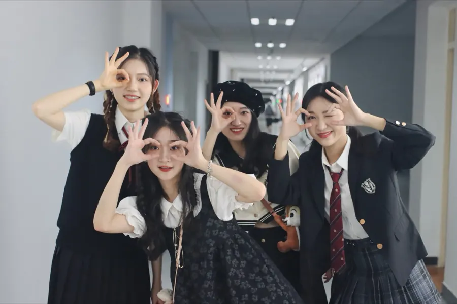 Four friends in a corridor, making glasses with their fingers.