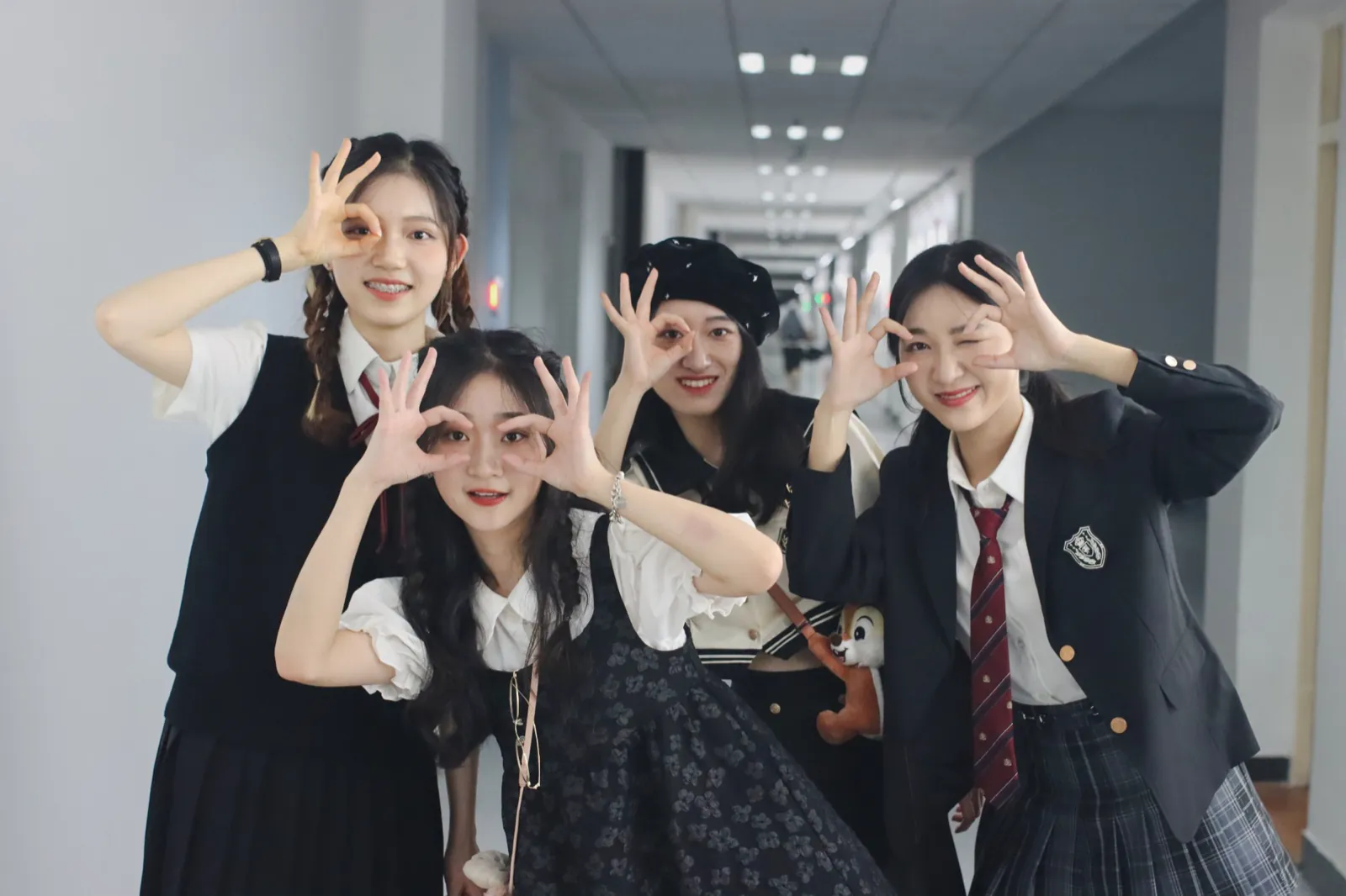 Four friends in a corridor, making glasses with their fingers.