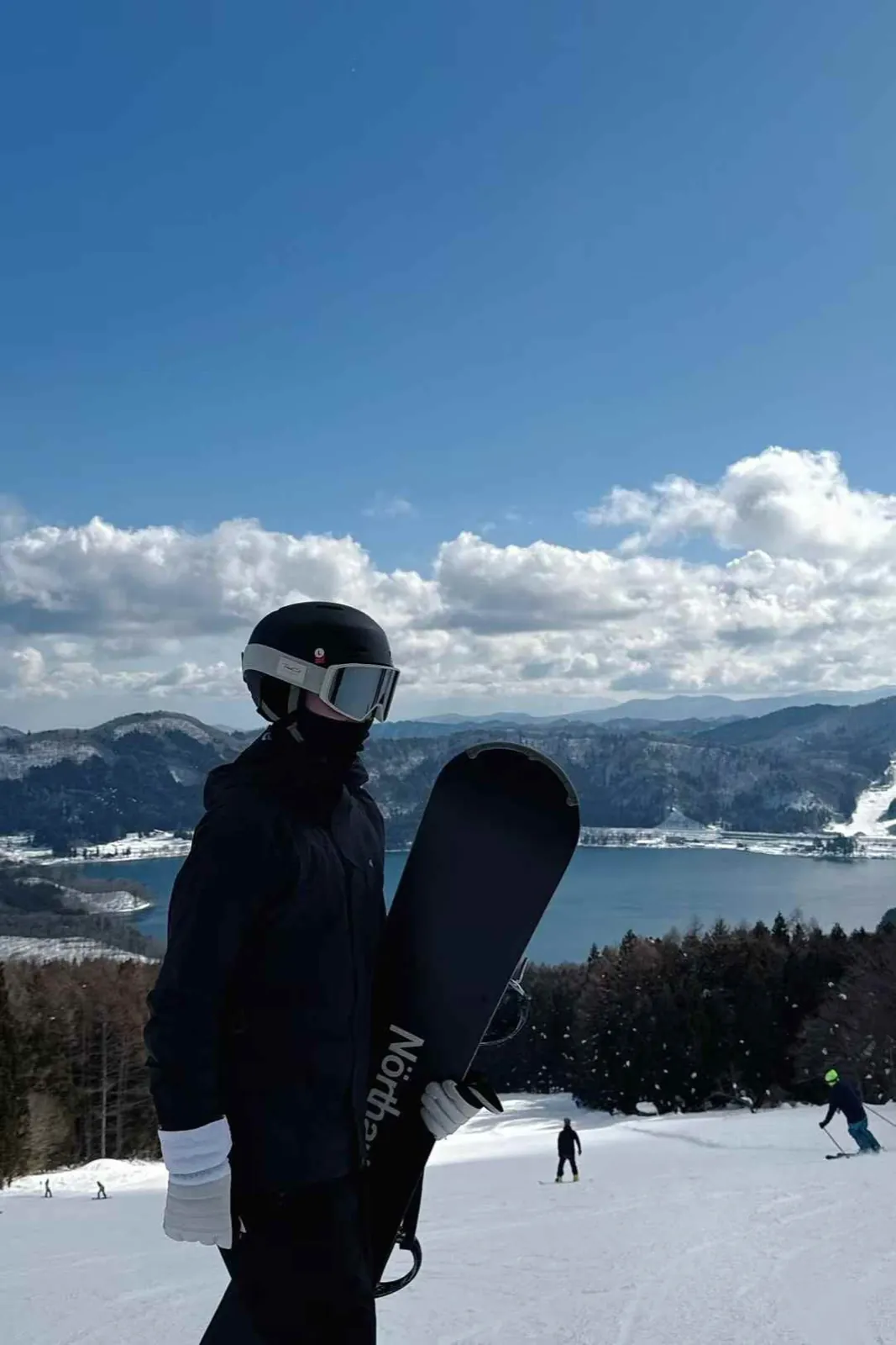 Board in hand at the top, a lake and clouds behind.