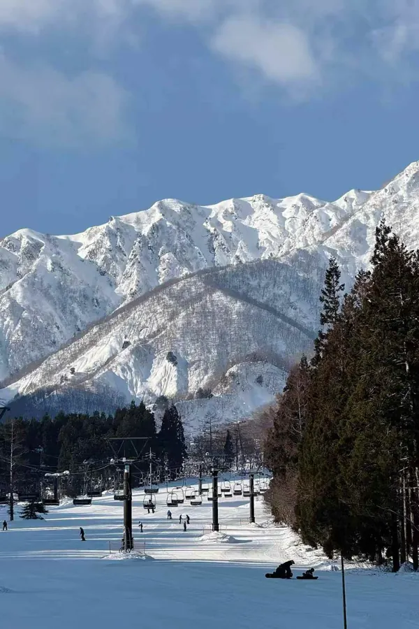 Jagged snow-covered peaks above a busy run.