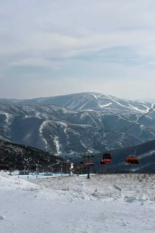Chairlifts crossing a valley, trails cut into the mountains behind.