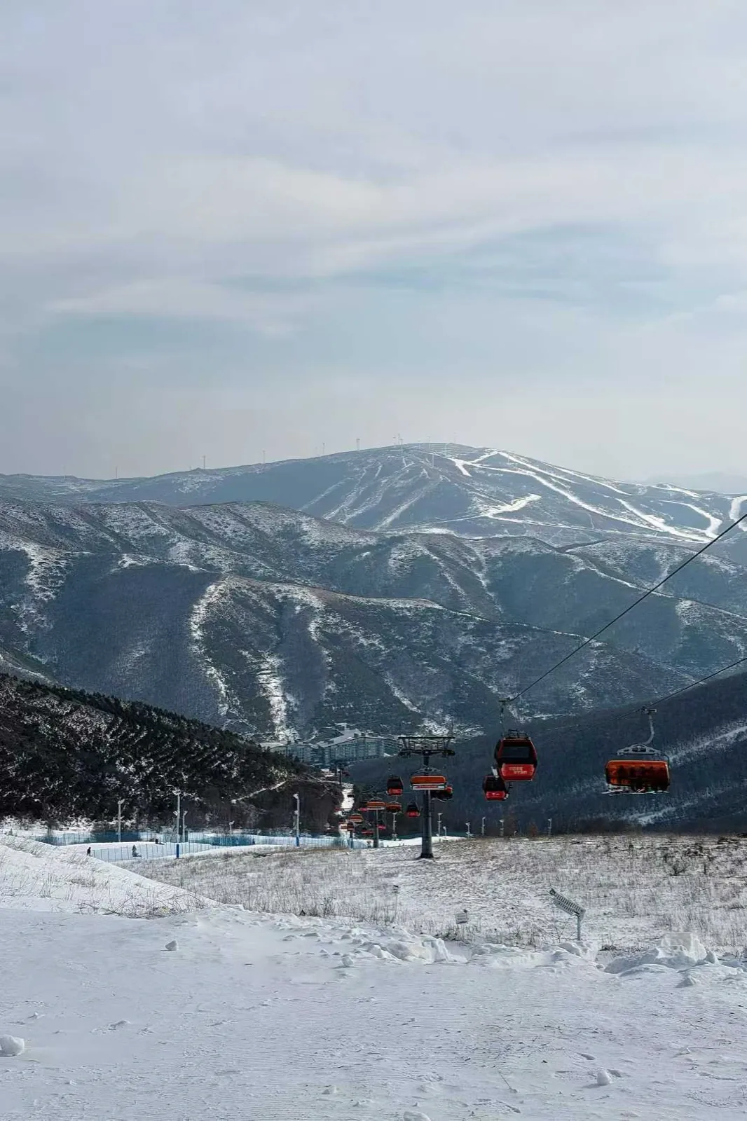 Chairlifts crossing a valley, trails cut into the mountains behind.