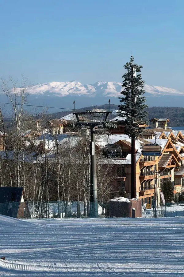 A groomed run above a resort village, snowy peaks on the horizon.