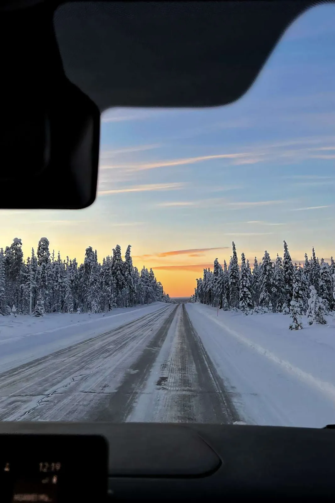 A snowy road through the forest at sunrise.